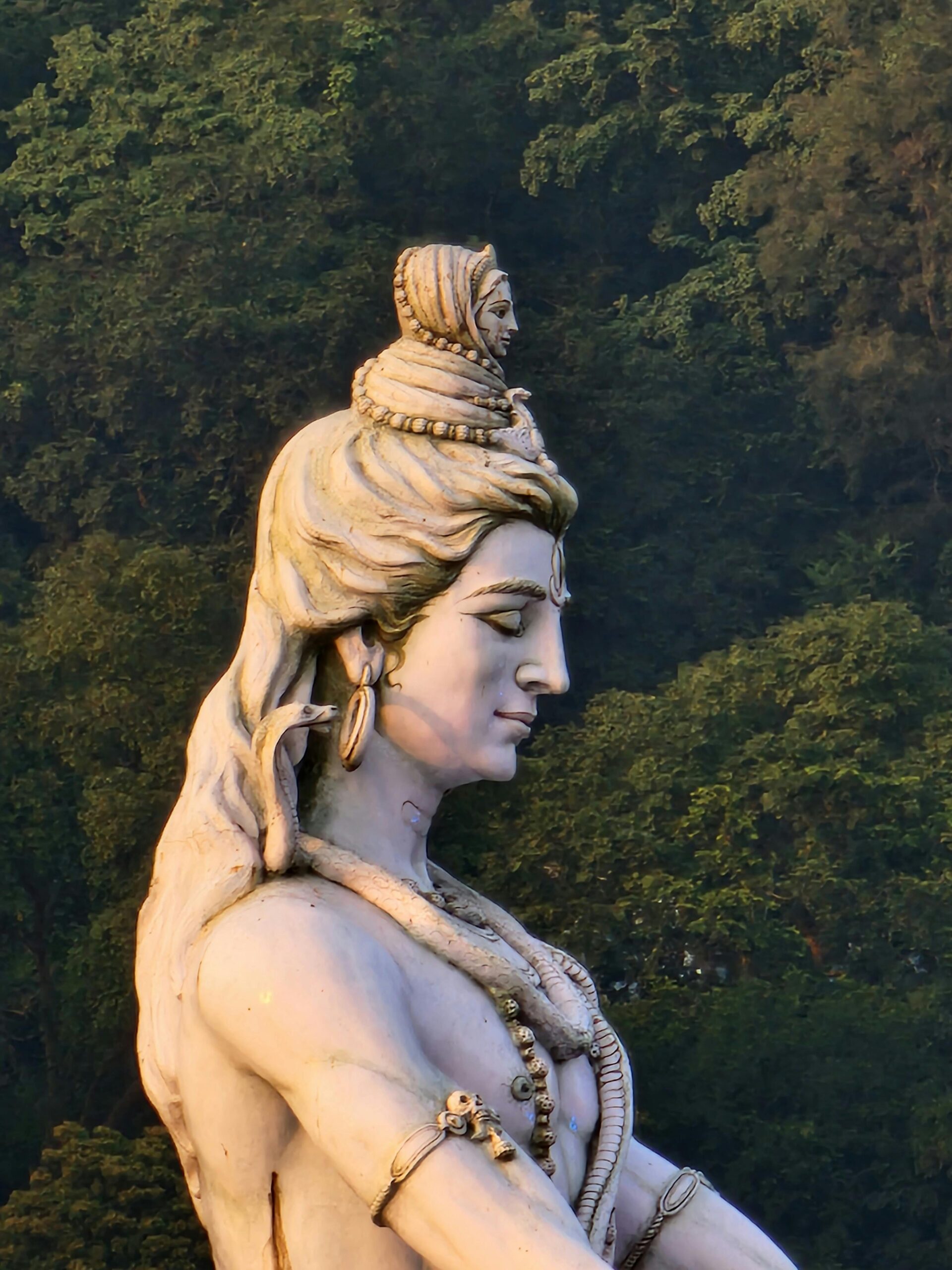 A serene statue of Lord Shiva surrounded by lush greenery in Rishikesh, India.