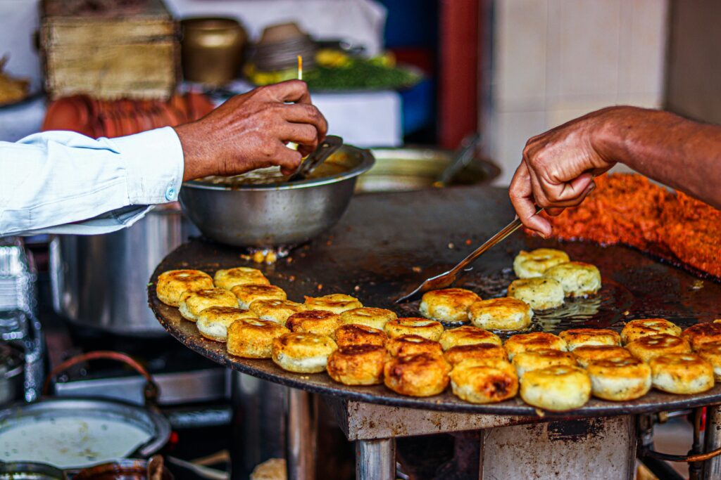 Varanasi Travel Guide: Where Life, Death, and Spirituality Meet Close-up of a street vendor preparing traditional fried snacks on an outdoor grill.