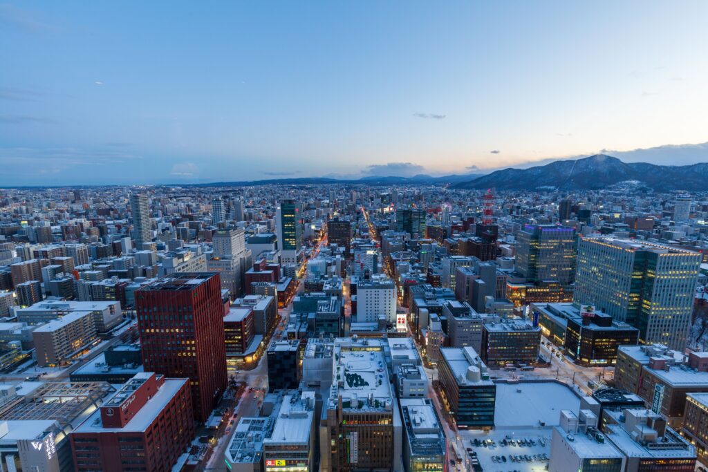 Best Places to Visit in Japan in 2026: 25 Amazing Must-See Gems Captivating aerial view of Sapporo, Japan in winter at dusk with snow-covered buildings and distant mountains.