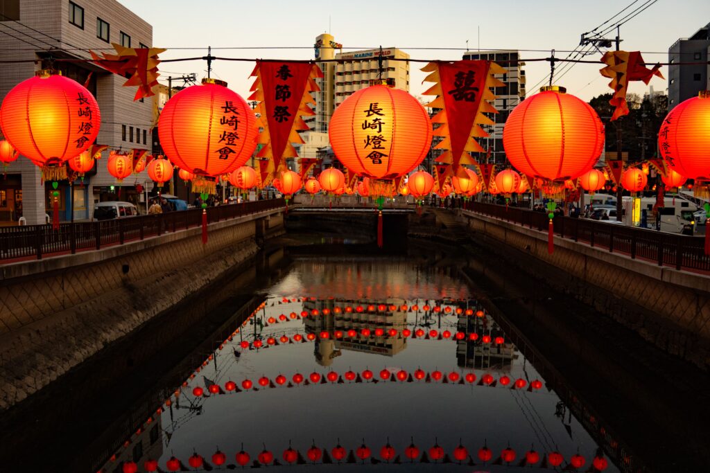 Best Places to Visit in Japan in 2026: 25 Amazing Must-See Gems Brightly lit lanterns line a canal in Nagasaki, Japan, reflecting vibrantly in the calm water.